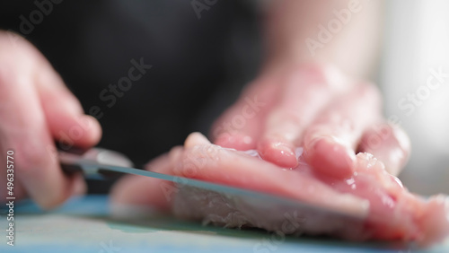 Hands cut turkey pink meat with sharp knife close-up