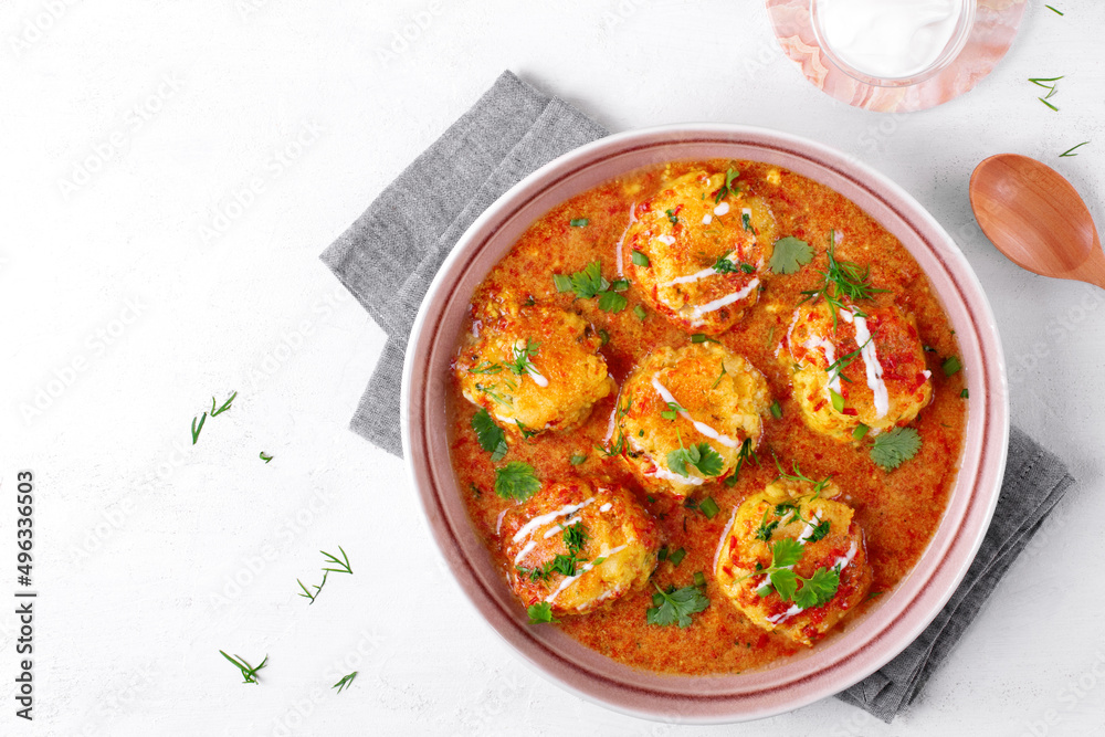 Malai Kofta served with yogurt and fresh herbs. Hot meal with potato and paneer cheese balls in tomato sauce. Indian cuisine. Top view Malai Kofta served with yogurt and fresh herbs. Hot meal with potato and paneer cheese balls in tomato sauce. Indian cuisine. Top view