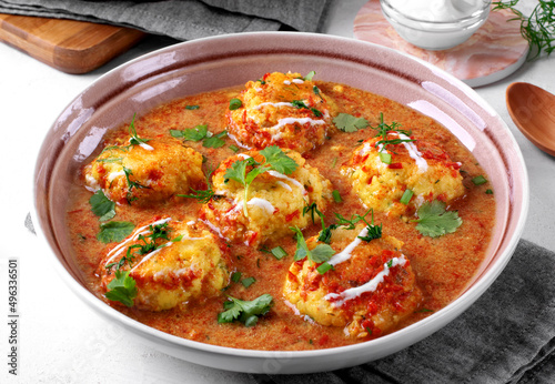 Malai Kofta served with yogurt and fresh herbs. Hot meal with potato and paneer cheese balls in tomato sauce. Indian cuisine