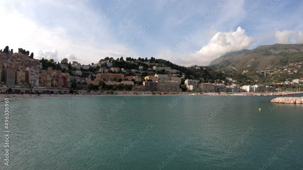 Menton, France, October 2, 2021: PAN SHOT SLOW MOTION - The Sablettes beach in Menton is located between the two ports (the Old Port and Garavan), along the Quai Bonaparte and the old town. Menton, France, October 2, 2021: PAN SHOT SLOW MOTION - The Sablettes beach in Menton is located between the two ports (the Old Port and Garavan), along the Quai Bonaparte and the old town.