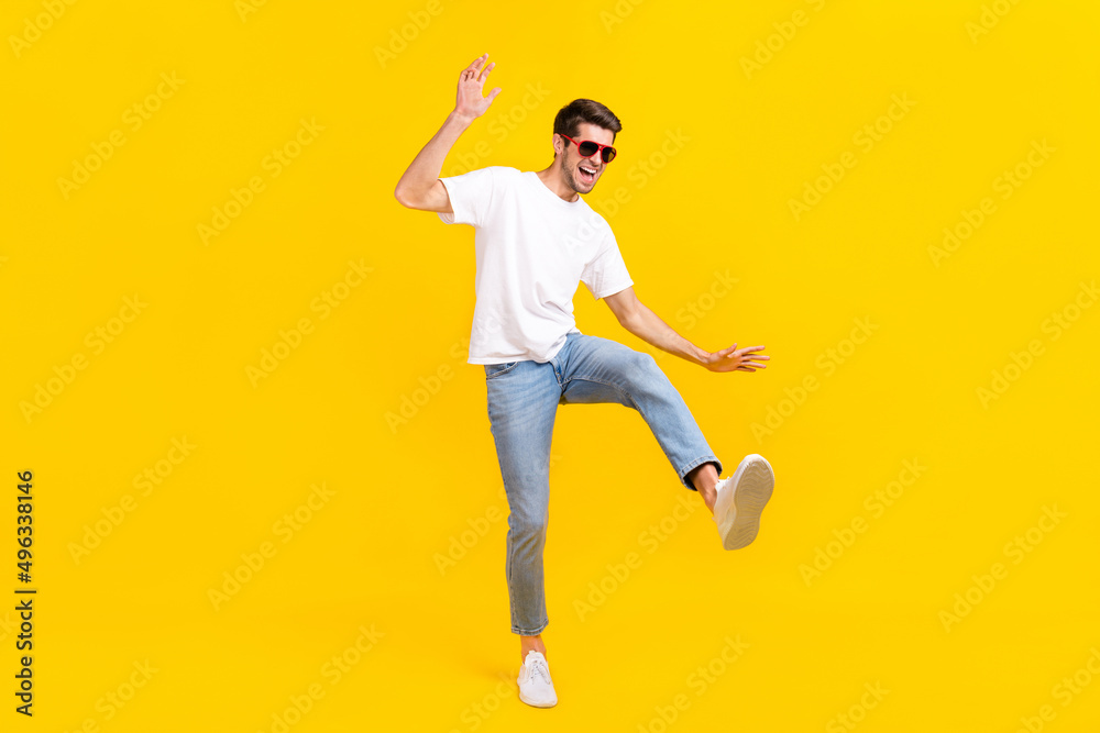 Full body photo of cool young brunet guy dance wear eyewear t-shirt jeans footwear isolated on yellow background Full body photo of cool young brunet guy dance wear eyewear t-shirt jeans footwear isolated on yellow background