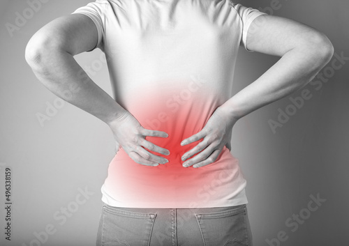 Woman suffering from lower back pain with red spot. Sport injury, chronic diseases. Health care and medicine concept. High quality photo