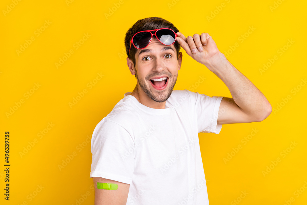 Photo of impressed young brunet guy did vaccination wear glasses t-shirt isolated on yellow color background Photo of impressed young brunet guy did vaccination wear glasses t-shirt isolated on yellow color background
