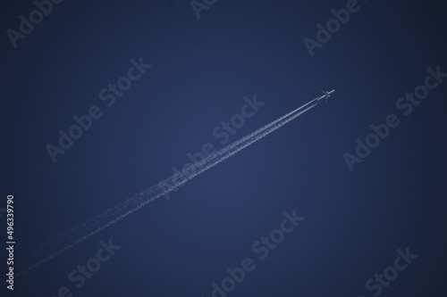 Aereo e scia di condensazione su cielo terso photo