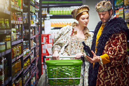 Its a vintage fit for a king and queen. Shot of a king and queen looking at goods while shopping in a modern grocery store. photo