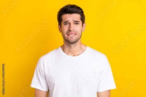 Photo of sorry worried nervous scared man bite lip look camera wear white t-shirt isolated yellow color background