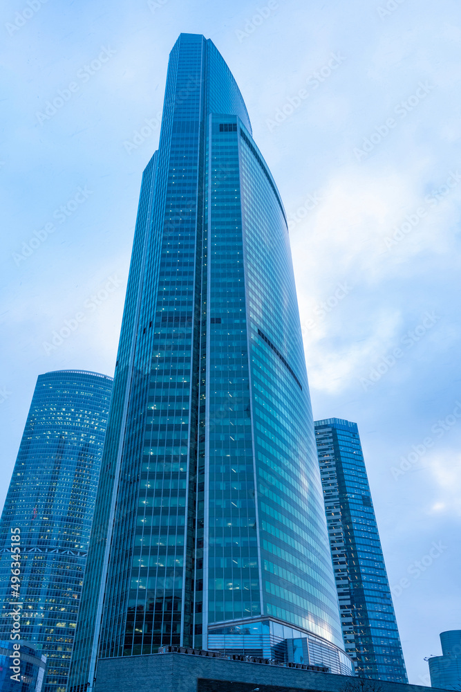 The tops of modern corporate buildings in snowfall. Low angle view of skyscrapers.