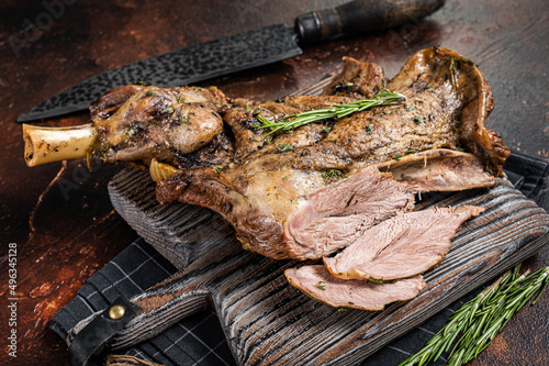 Slow Cooked grilled lamb mutton shoulder meat with herbs and spices on wooden board. Dark background. Top view