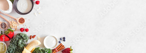 Healthy food corner border. Smoothie making concept. Top view on a white marble banner background. Copy space. Fruit, yogurt, almond milk and an assortment of ingredients.