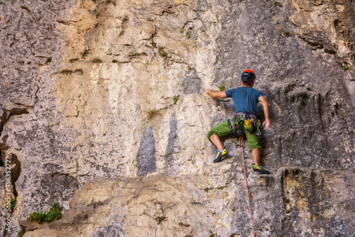 Young man climbs on a rocky wall in a cave. Man climbing on a big limestone wall.