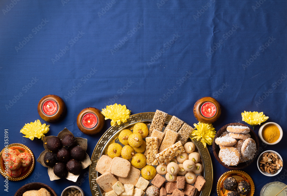 traditional indian sweets on blue background with candles and flowers flat  lay Stock Photo | Adobe Stock