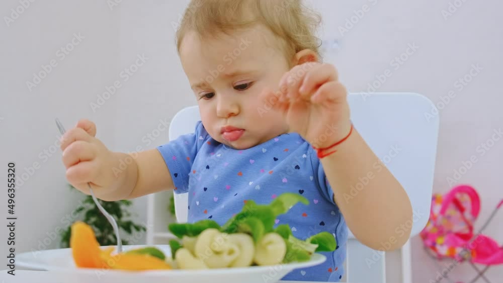The child eats pasta and vegetables. Selective focus. The child eats pasta and vegetables. Selective focus.