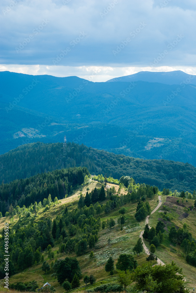 Mountain path going into the distance. Cell tower on the mountain. Green forest on the mountainside. Tourist trail. Ukrainian Carpathians.