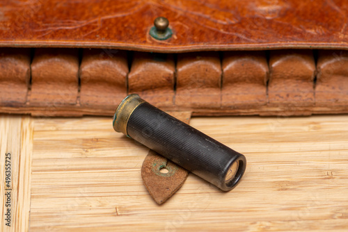 Hunting cartridge on the background of a leather bandolier on a textured background, close-up, selective focusing. Concept: bird hunting, hunting ammunition of large and small caliber.