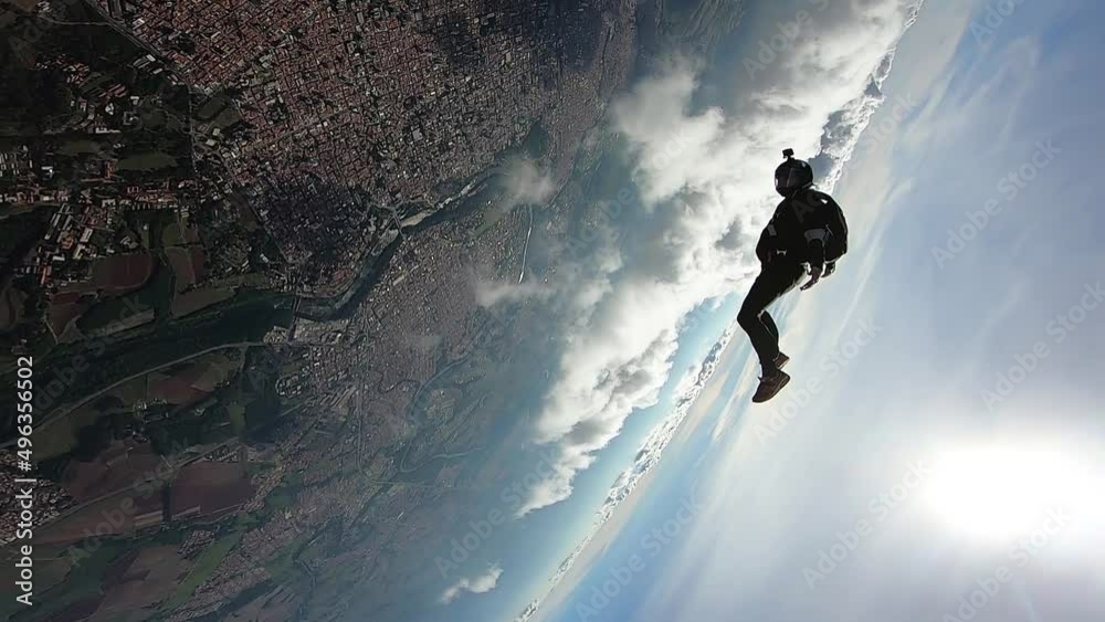 Parachutist in dive position on a sunny day and clouds in slow motion.