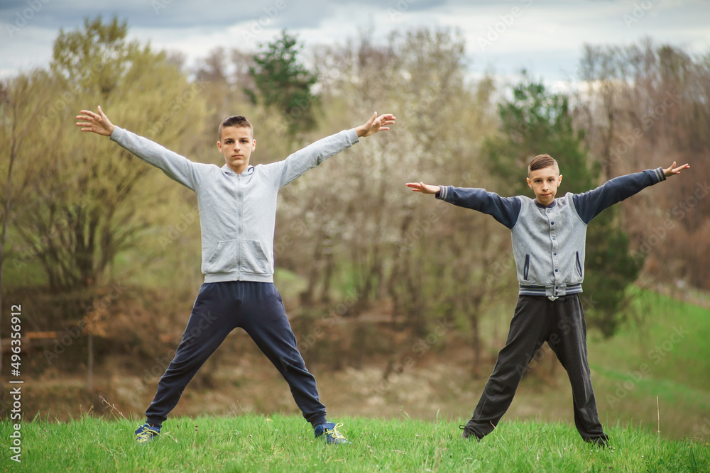 boys exercises outside, stretching his shoulder and back muscles boys exercises outside, stretching his shoulder and back muscles
