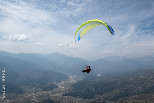 A paraglider carves a turn with views of Nepal, Himalayas in distance. photo