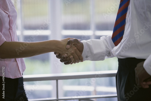 Mid section view of a businessman and a businesswoman shaking hands