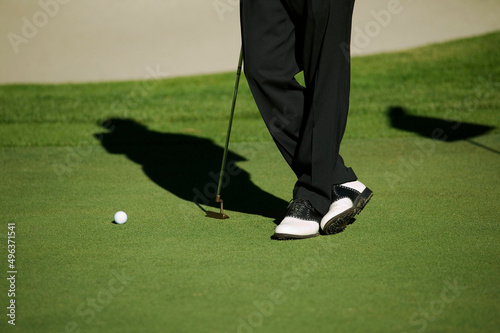 Low section view of a person standing with a golf club photo