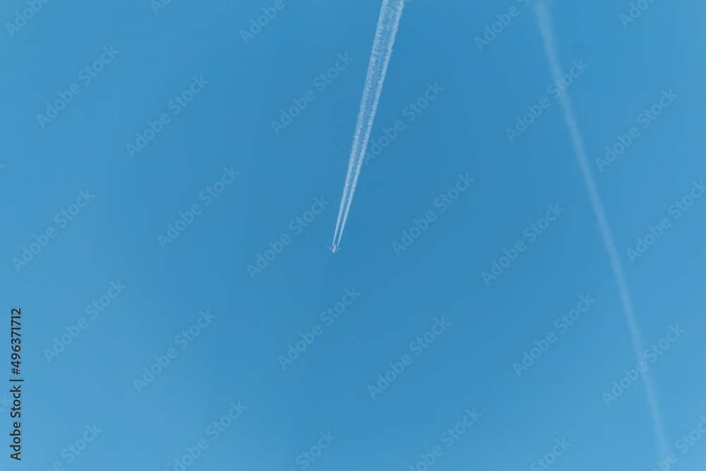 The plane flies through a clear blue sky, leaving long trails of steam behind it. Airplane in the sky. With copy space to add text.