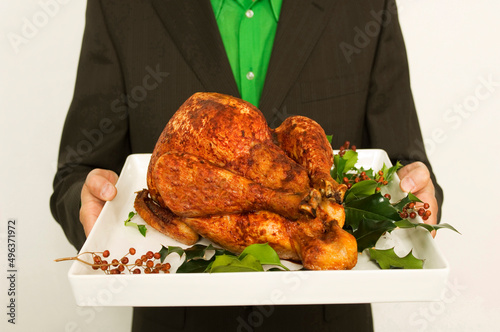 Mid section view of a man holding a roasted turkey on a tray