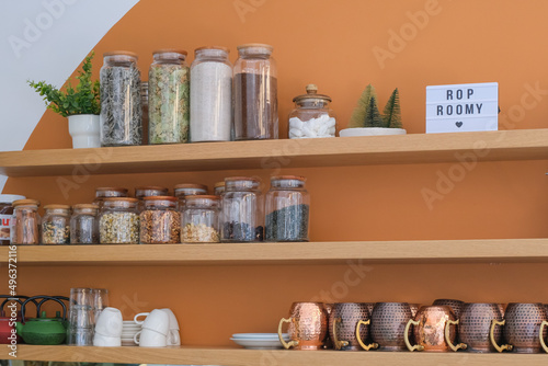 wooden shelves with tea leaves collection and spices in glass jars and vintage tea cups. coffee and tea shops interior