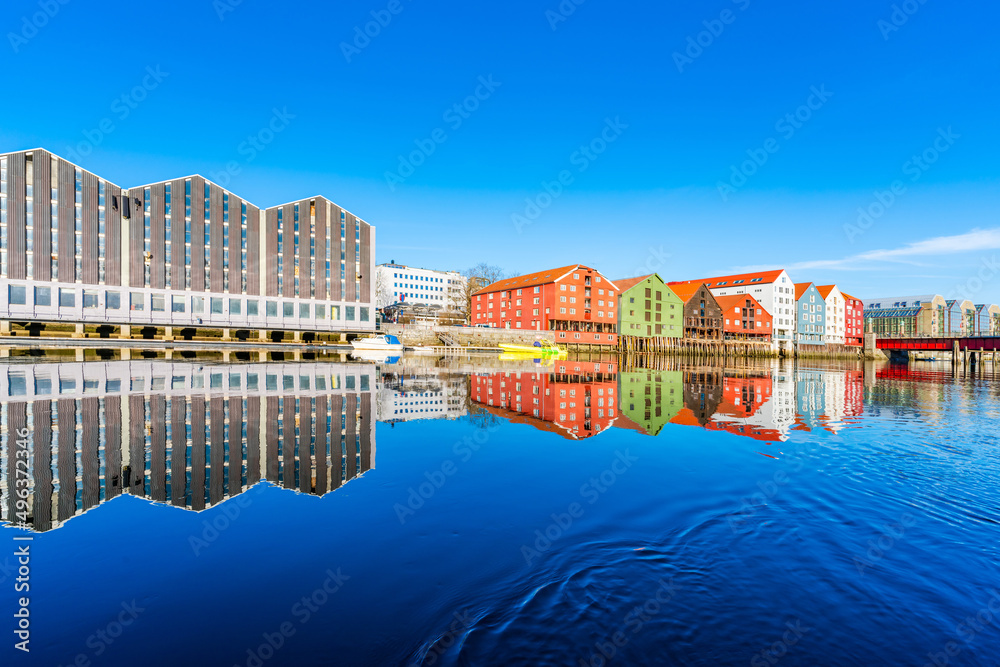 Colorful old wooden houses with reflections in the river Nidelva in the Brygge district of Trondheim, Norway