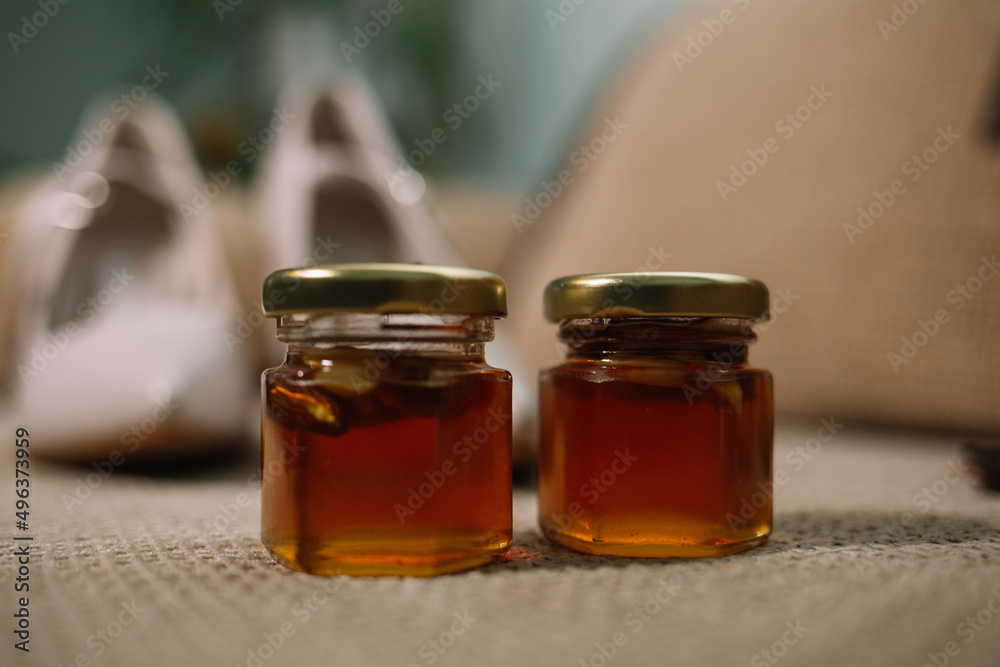 two jars of honey and wooden drizzler on table on yellow background two jars of honey and wooden drizzler on table on yellow background