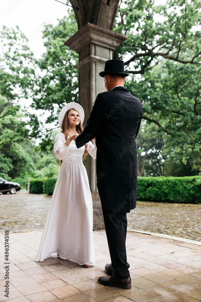 Happy young couple. Brides in hats. Young girl in a white wedding dress and hat with a bouquet of flowers. Brides in the castle. Bride and groom. Happy young couple. Brides in hats. Young girl in a white wedding dress and hat with a bouquet of flowers. Brides in the castle. Bride and groom.