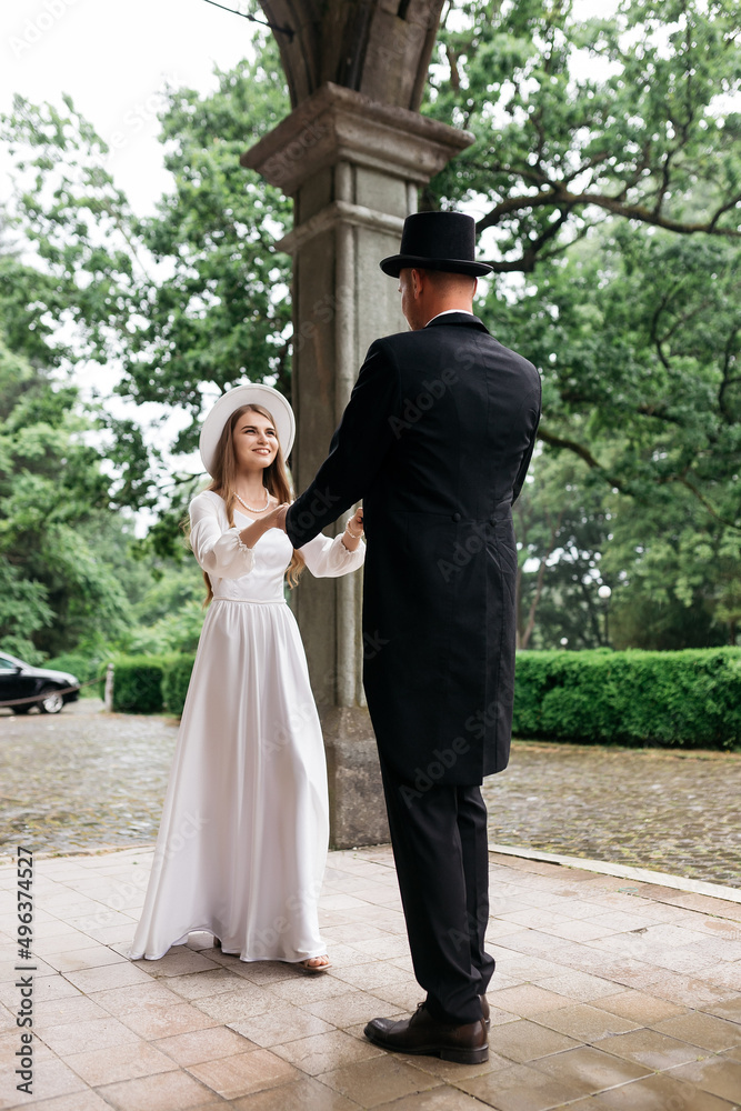 Happy young couple. Brides in hats. Young girl in a white wedding dress and hat with a bouquet of flowers. Brides in the castle. Bride and groom. Happy young couple. Brides in hats. Young girl in a white wedding dress and hat with a bouquet of flowers. Brides in the castle. Bride and groom.