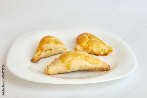 Delicious fragrant triangular baked cakes on a white plate