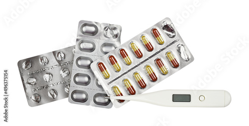 Pills in blisters and digital thermometer isolated on white photo