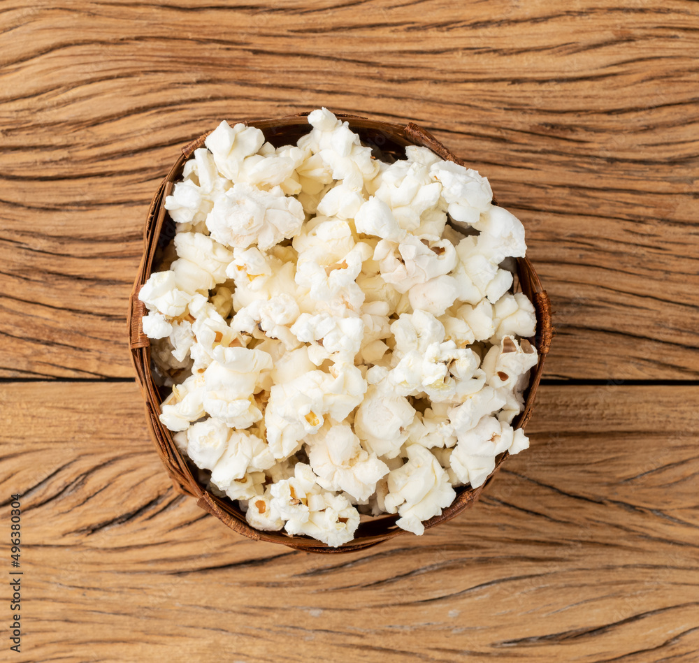 Popcorns in a basket over wooden table Popcorns in a basket over wooden table