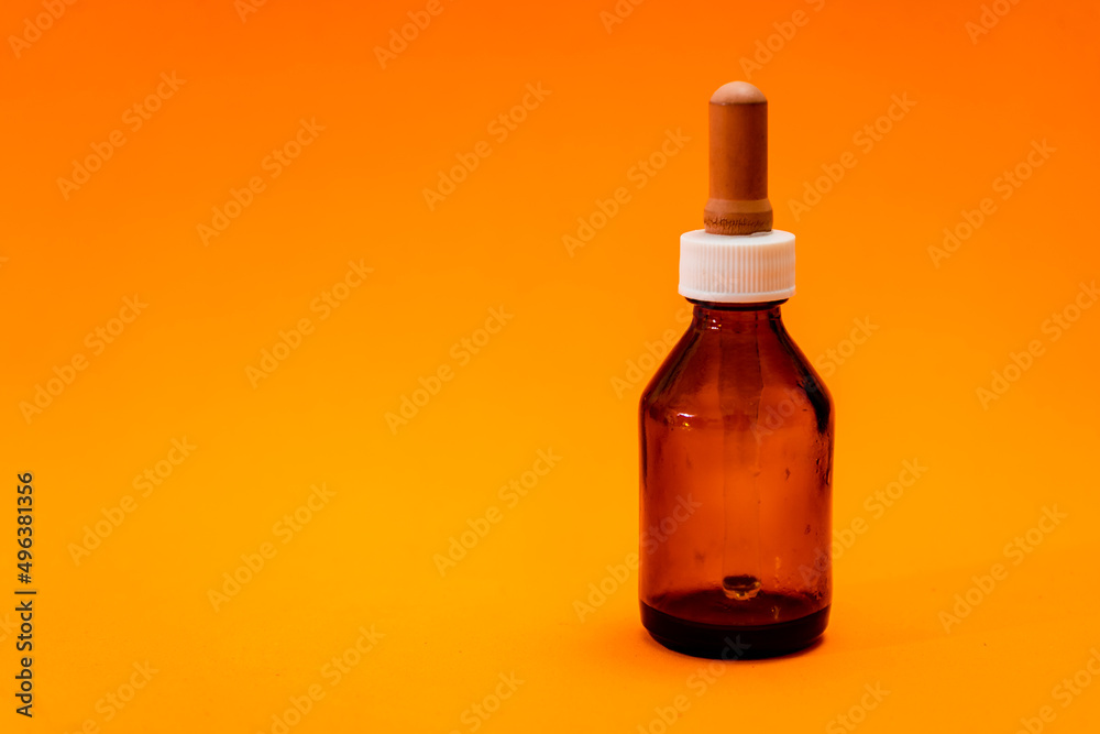 Small bottle with amber glass dropper insulated on orange background. Small bottle with amber glass dropper insulated on orange background.