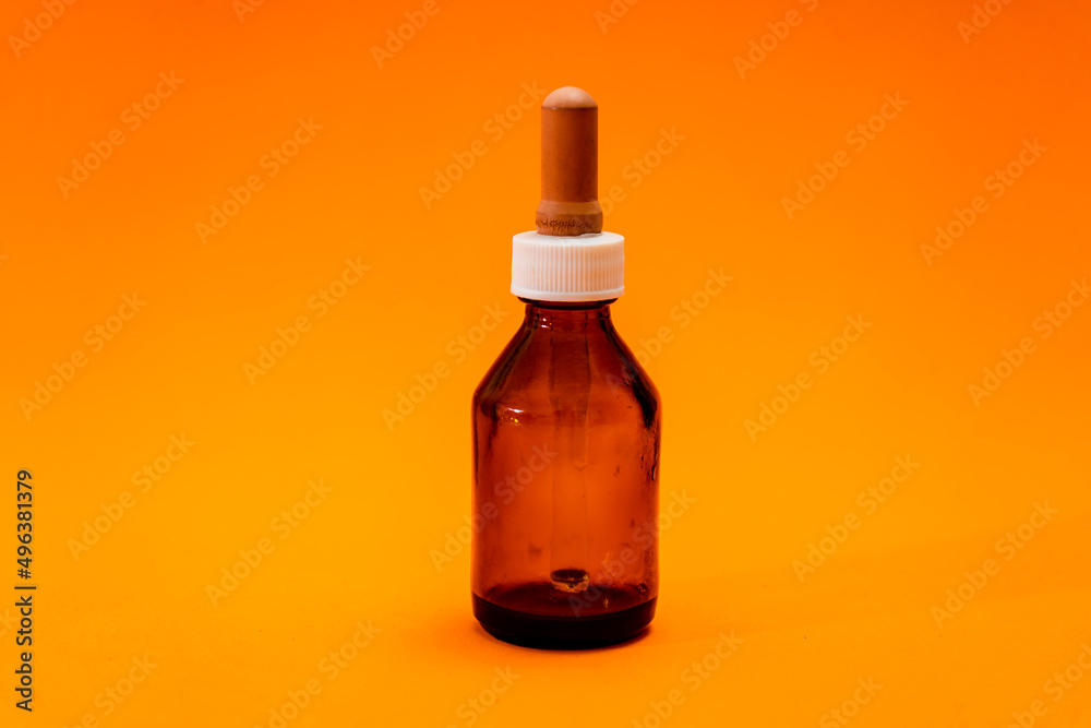 Small bottle with amber glass dropper insulated on orange background. Small bottle with amber glass dropper insulated on orange background.