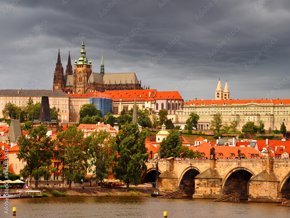 Prague castle, st. Vitus catedral and charles bridge in sunny day, dark dramatic stormy clouds behind. Prague historic city center. Landscape of famous prague old town, Czech Republic capital.