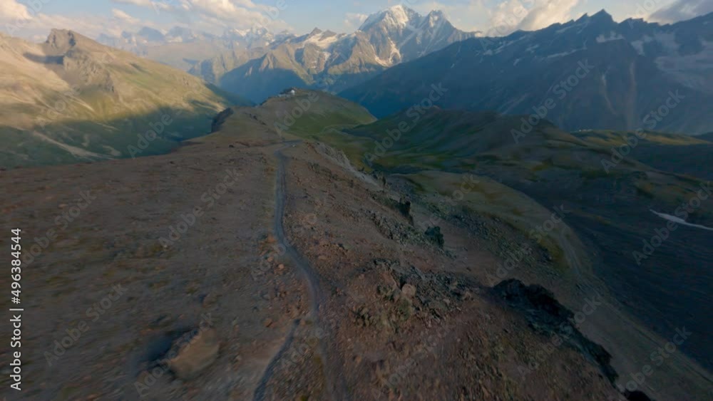Aerial view fast flying movement over natural textured crack cliff stone surface surrounded by picturesque sky horizon. FPV drone amazing mountain with snowy peak scenery wilderness air environment Aerial view fast flying movement over natural textured crack cliff stone surface surrounded by picturesque sky horizon. FPV drone amazing mountain with snowy peak scenery wilderness air environment