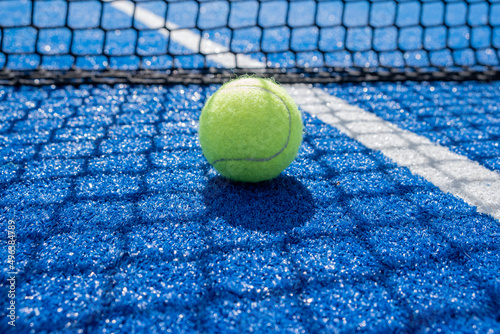 balls in the sun shade of the net on a blue paddle tennis court © Vic