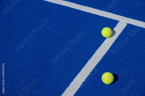 two balls next to the center line on a blue paddle tennis court © Vic