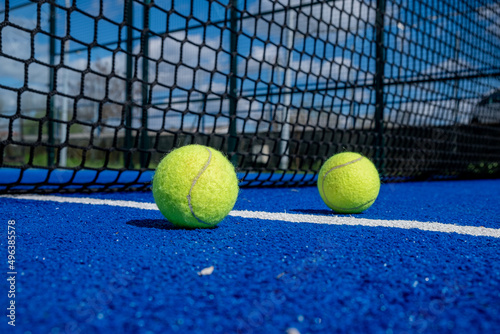 balls near the net in a blue paddle tennis court © Vic