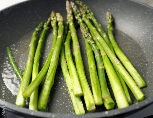 green asparagus fried in oil in a gray frying pan.  vegetarianism.  healthy food