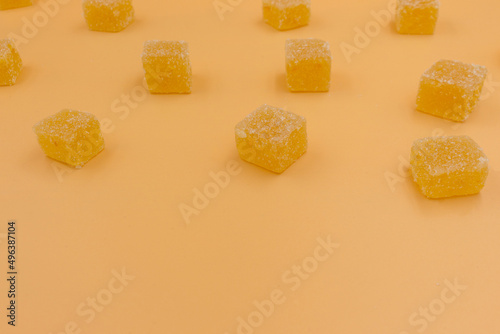 Candy orange marmalade in the form of cubes on an orange background. Flat ley
