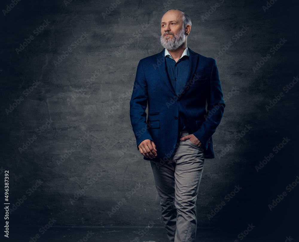 Elegant old man dressed in dark blue jacket against dark background