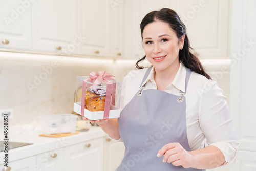 female cook with Kraffin, easter cake in a box with satin ribbon in the kitchen.
