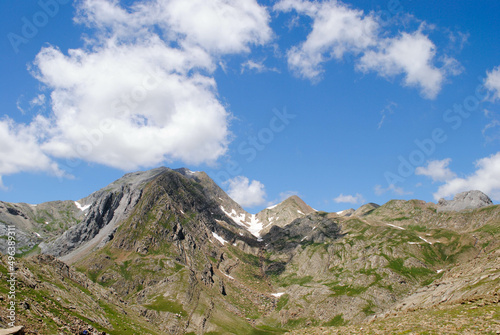Mountainous landscape of long green mountain ranges with a clear blue sky with few clouds