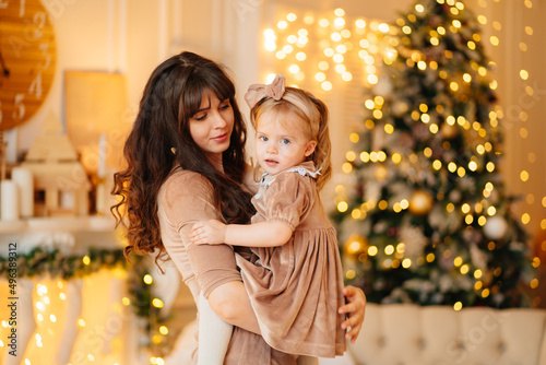 beautiful mother and daughter in elegant velour dresses in the New Year's room
