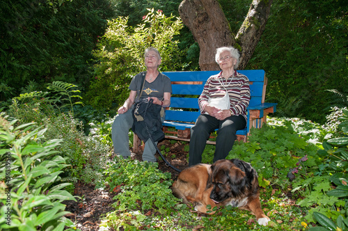 zwei seniorinnen sitzen im schatten auf einer bank