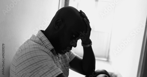 Photography Black African man sitting on floor home in worry, unemployed person