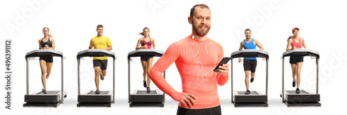 Man in sportswear with earphones holding a smartphone in front of people on treadmills