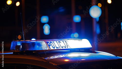 Radiowóz policji na sygnale wieczorem w mieście alarmowo do wypadku na światłach.